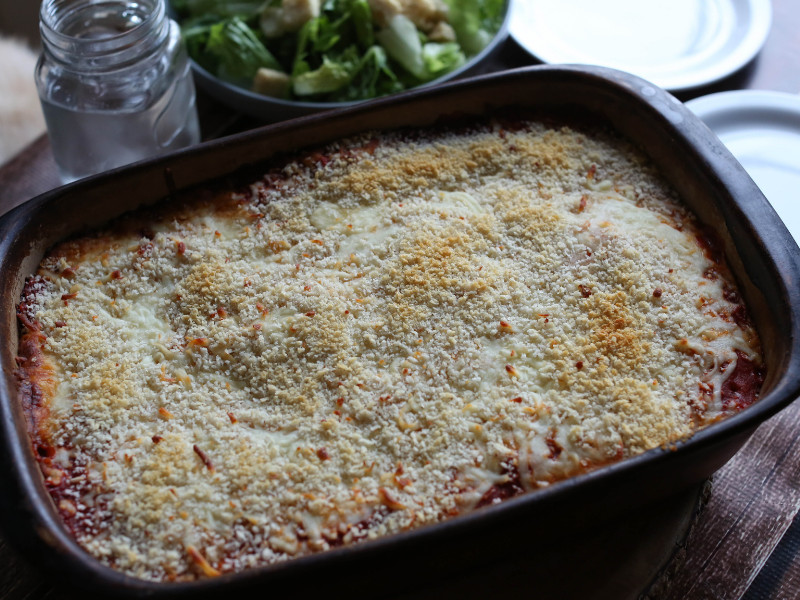 Freezer Meals - Chicken Parmesan prepared for dinner with side salad on glass of water.
