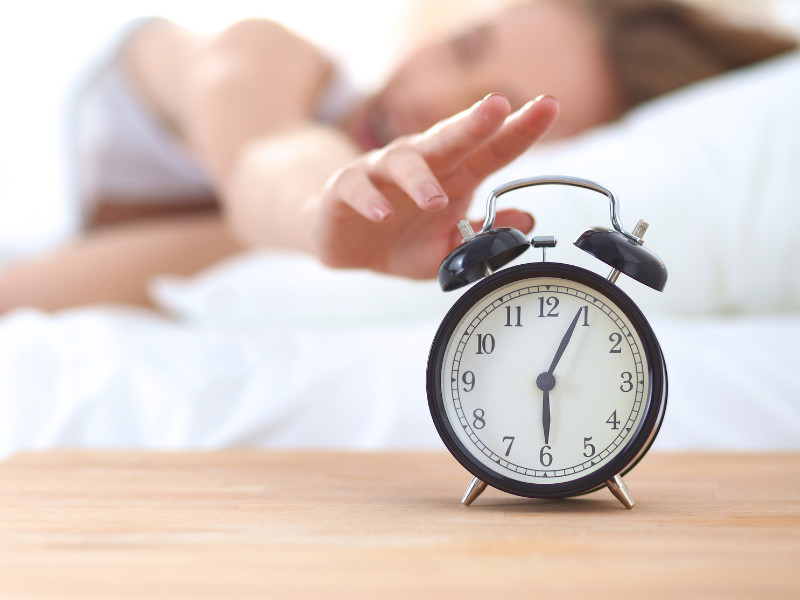 How to Get a Better Night’s Sleep - woman rising to alarm clock